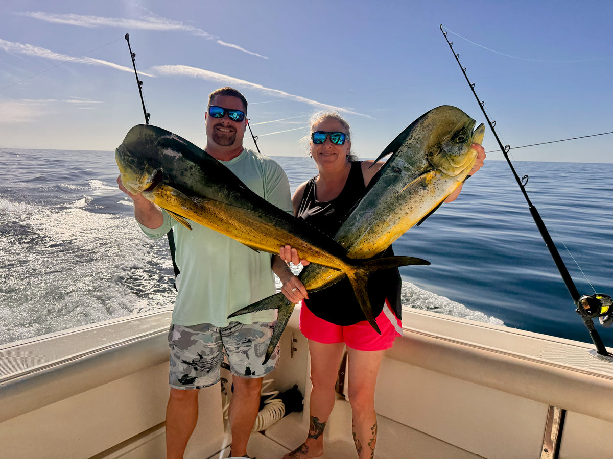 two people holding mahi mahi fish